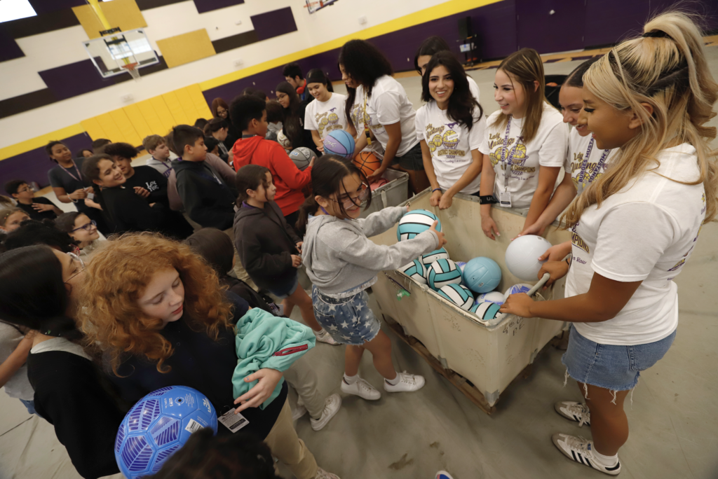 Burges High School girls basketball team passes sports balls to Hartley PK-8 Students