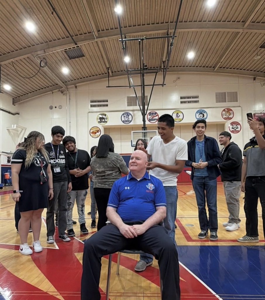Irvin High School Principal Bobby Stives smiles as students bedazzle his head with silver, red, and blue gems