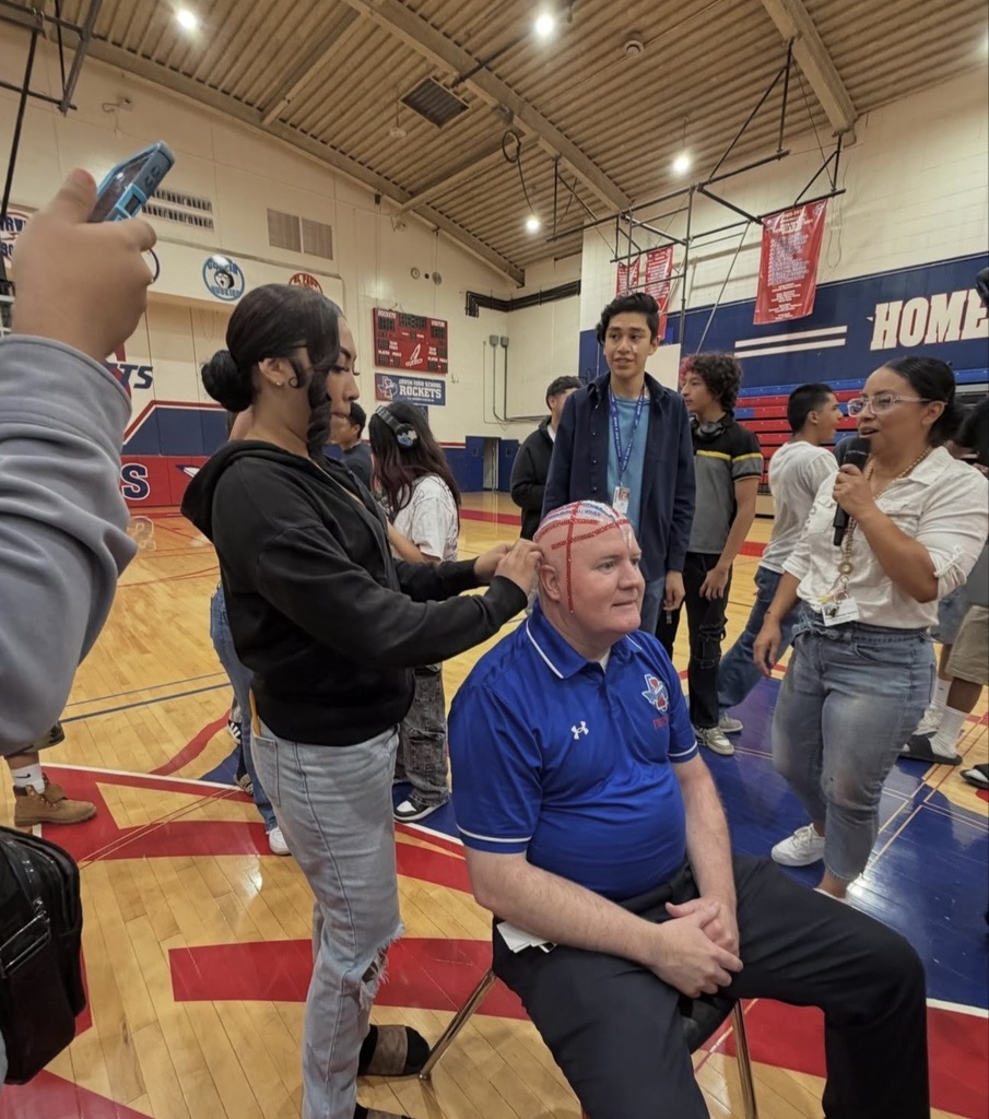 Irvin High School Principal Bobby Stives smiles as students bedazzle his head with silver, red, and blue gems