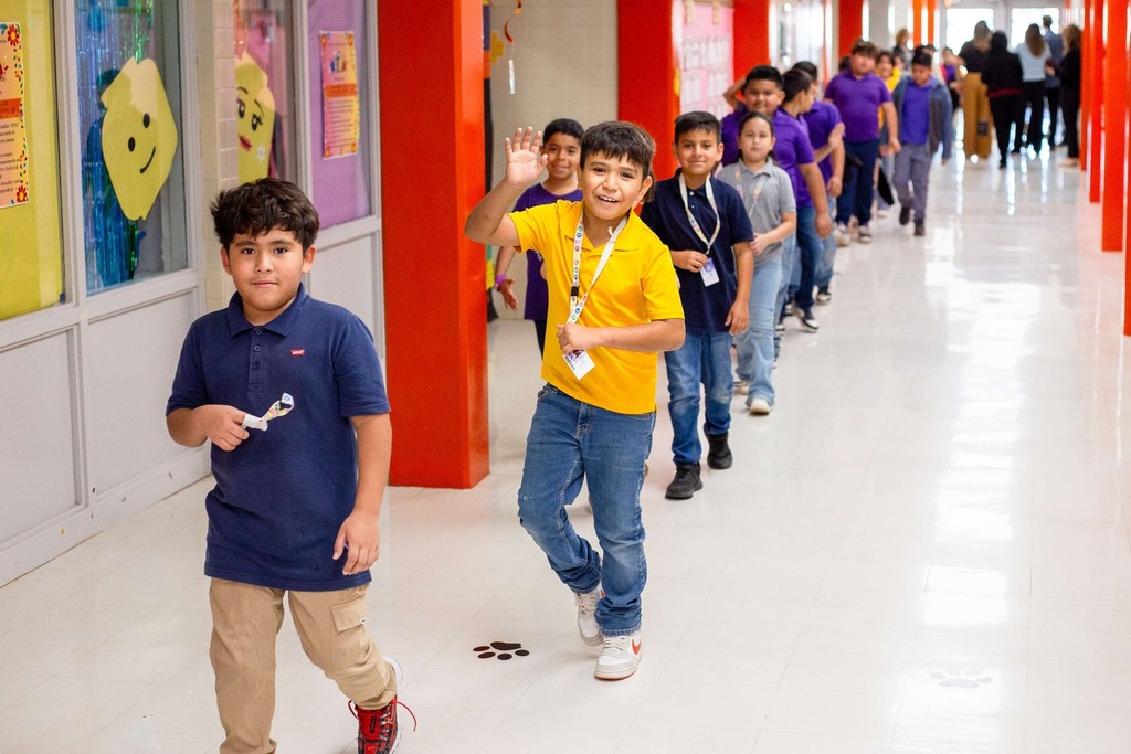 Students walking in a line and one waving at camera