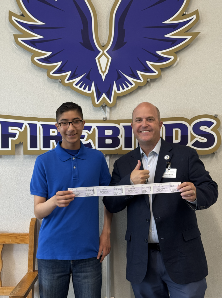 Attendance Challenge Murphree PK-8 Student winner takes photo with prize and education foundation manager Russel Booth