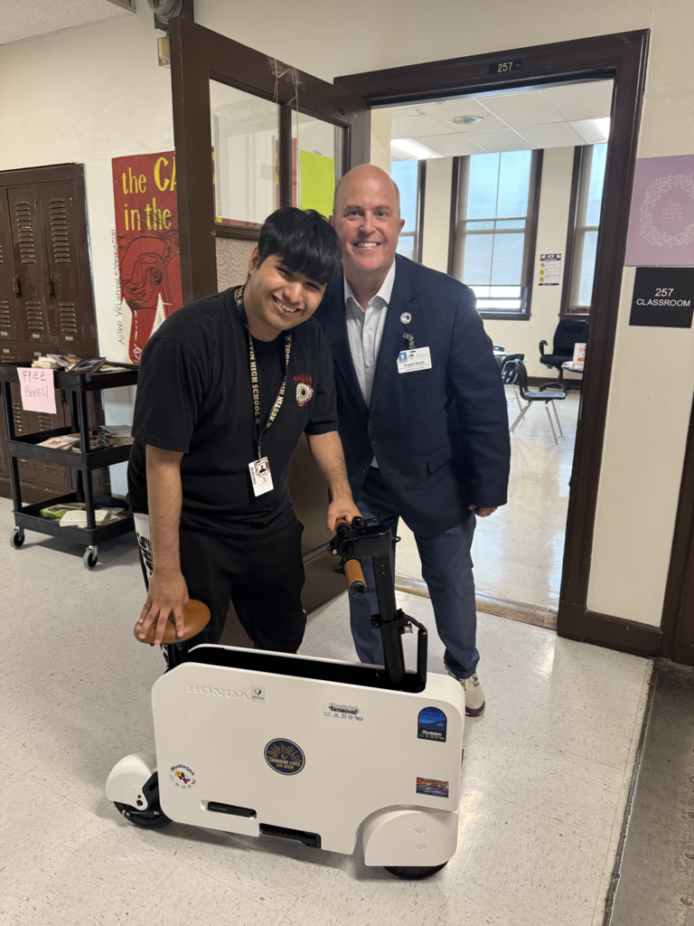 Attendance Challenge Austin High School Student winner takes photo with prize and education foundation manager Russel Booth and electric scooter