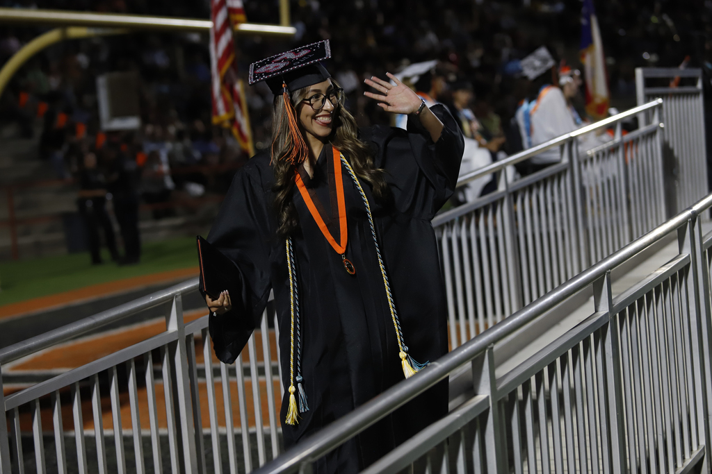 El Paso High School graduate smiles while waving at friends after receiving their diploma