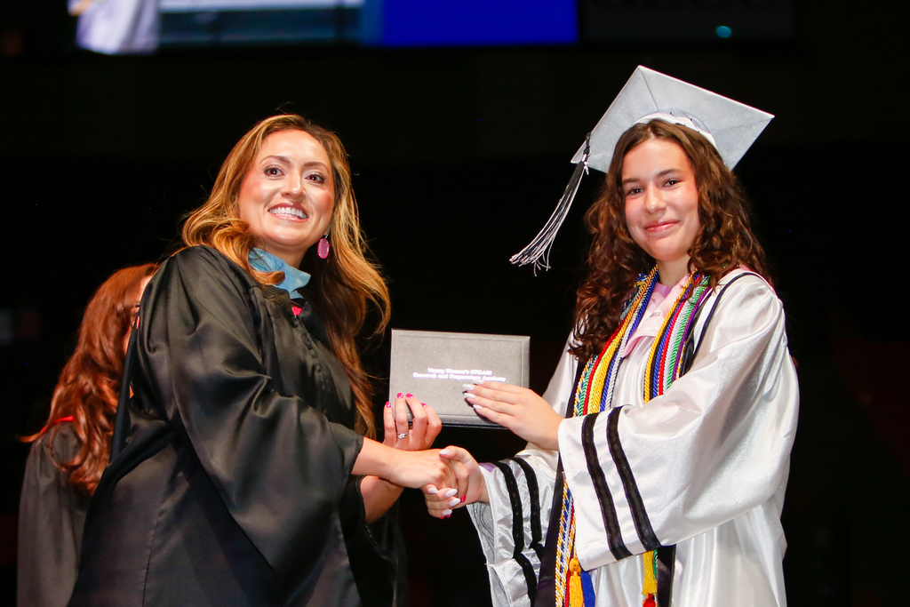 YWA student smiles for a photo with principal and diploma