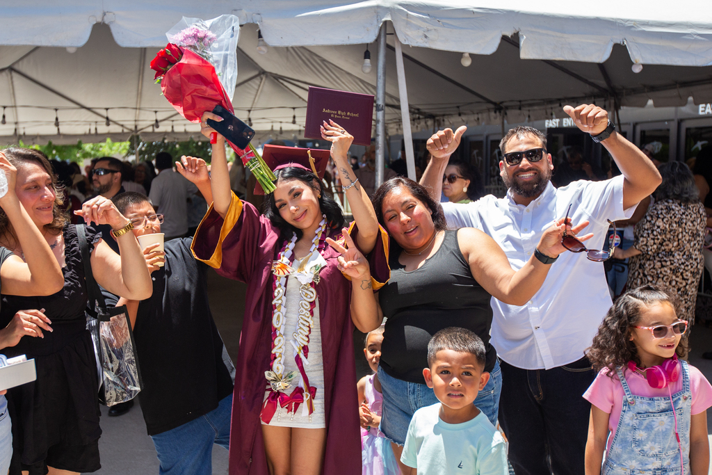 Andress graduate and their family smiling with hands in the air