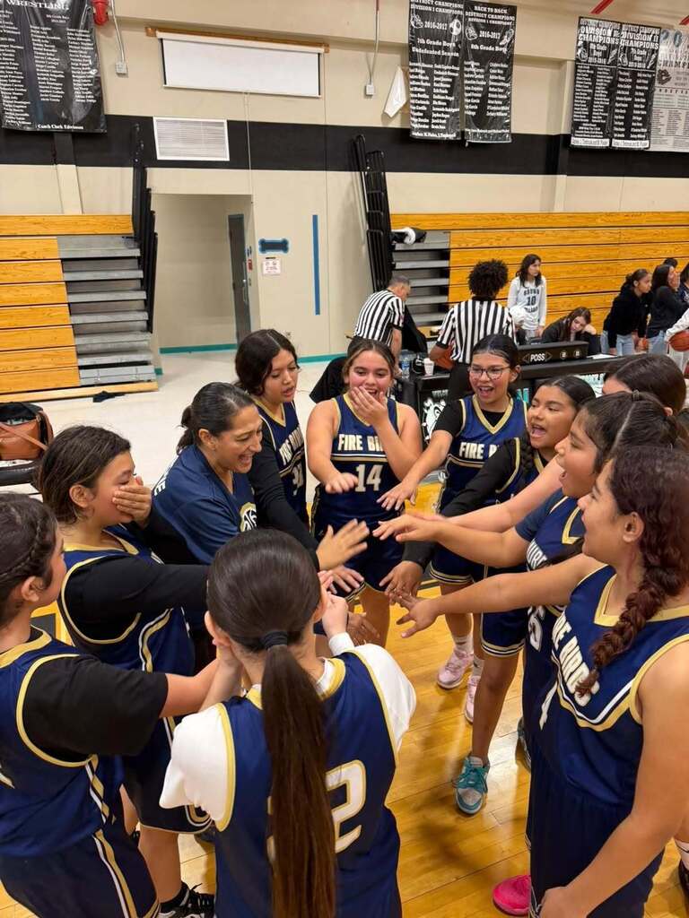 Murphree girls basketball team cheers in a circle while putting hands in the middle to break