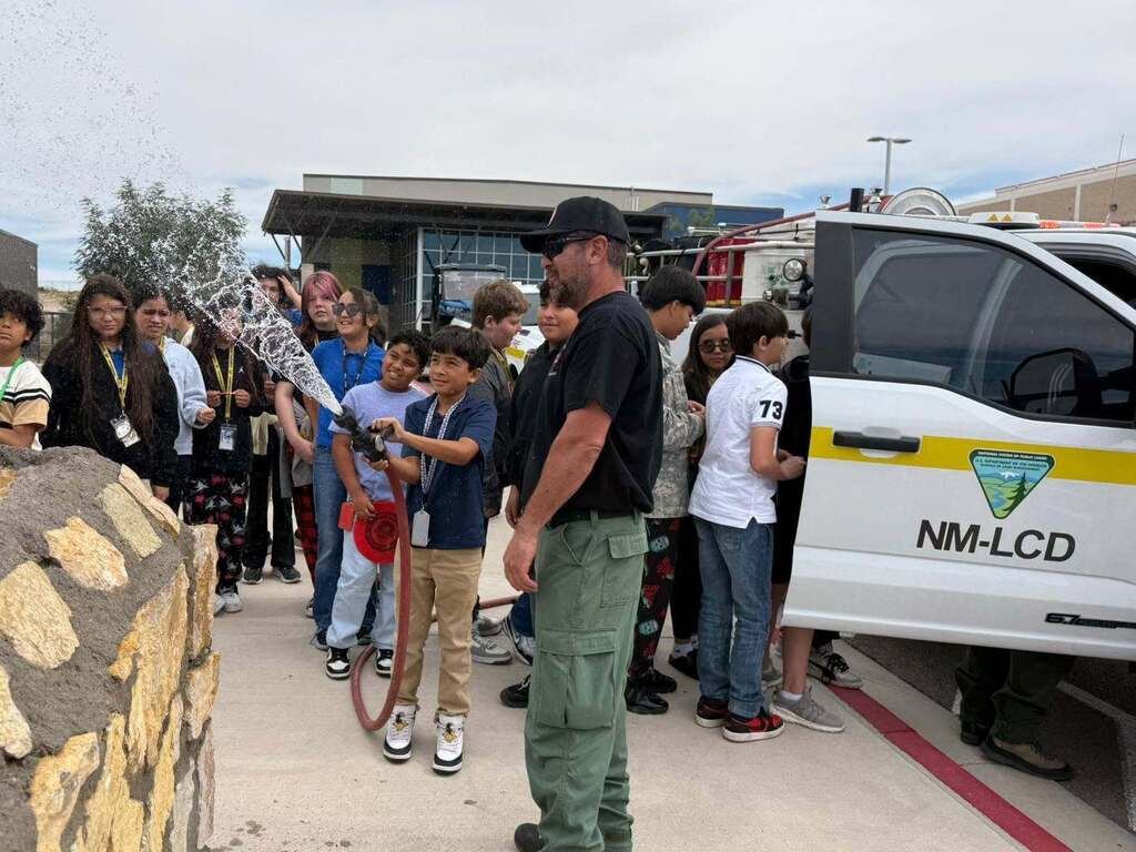 Murphree student using firefighters water hose while other students watch