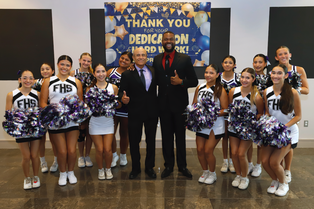 Ramon Rosales Jr. of Lundy Elementary School and John Matthews of Jefferson Silva High School smile for a photo with the Franklin High School cheerleaders