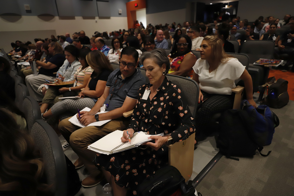 District and campus leadership review papers at summer conference at Irvin High School's auditorium