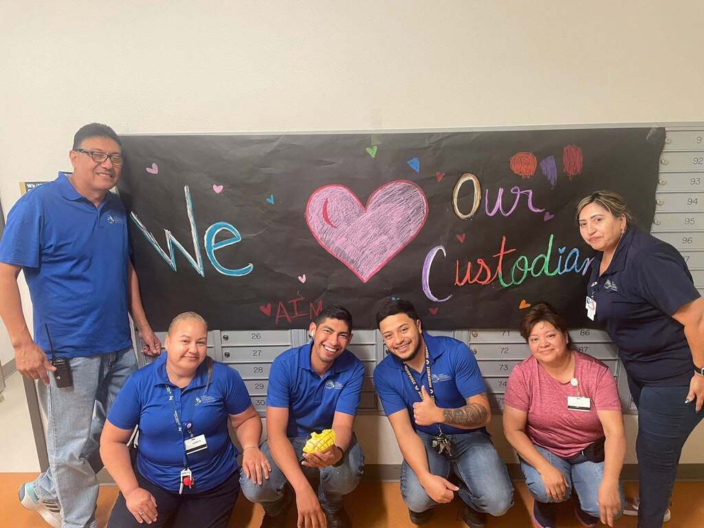 Murphree PK-8 custodians take a group photo in front of we love our custodians sign
