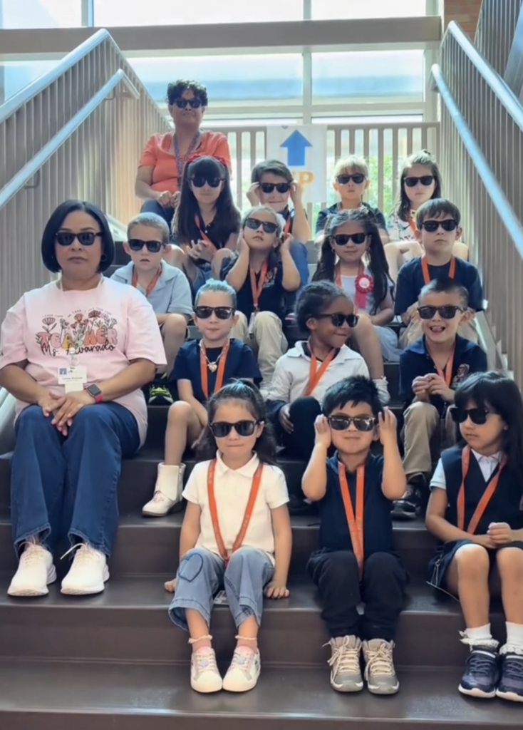Haskins students and two teachers smile with sunglasses on, on school stairs