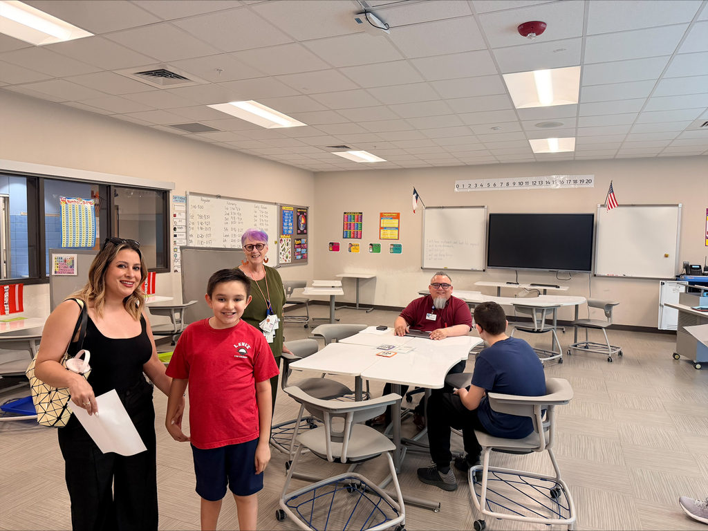 Family smiles for a photo with teachers during open house night 