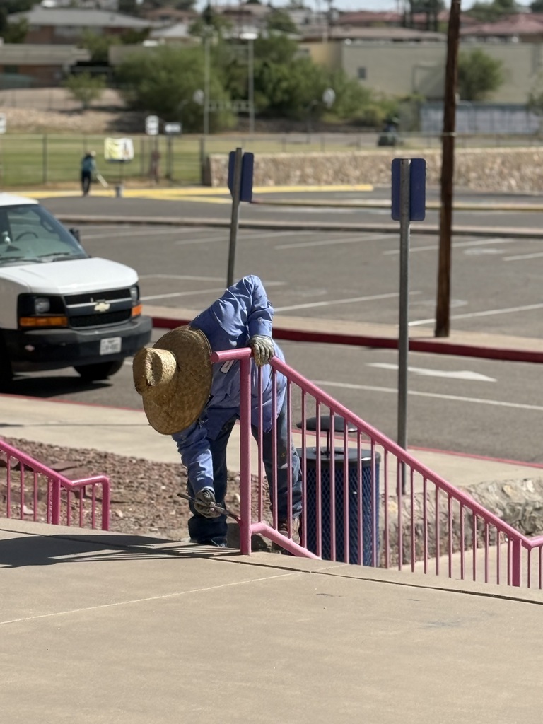 EPISD Operations worker repainting campus rails with bright prink paint