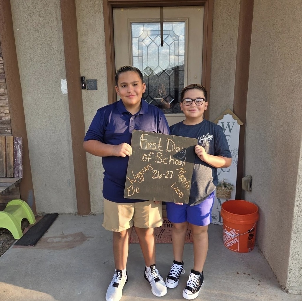 Mesita Elementary and Wiggs Middle School brothers smile for a picture at home holding a first day of school sign