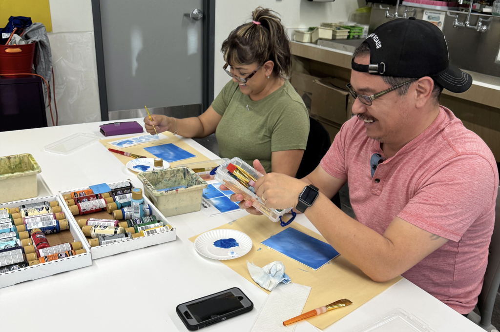 Two El Paso ISD employees smile while painting together