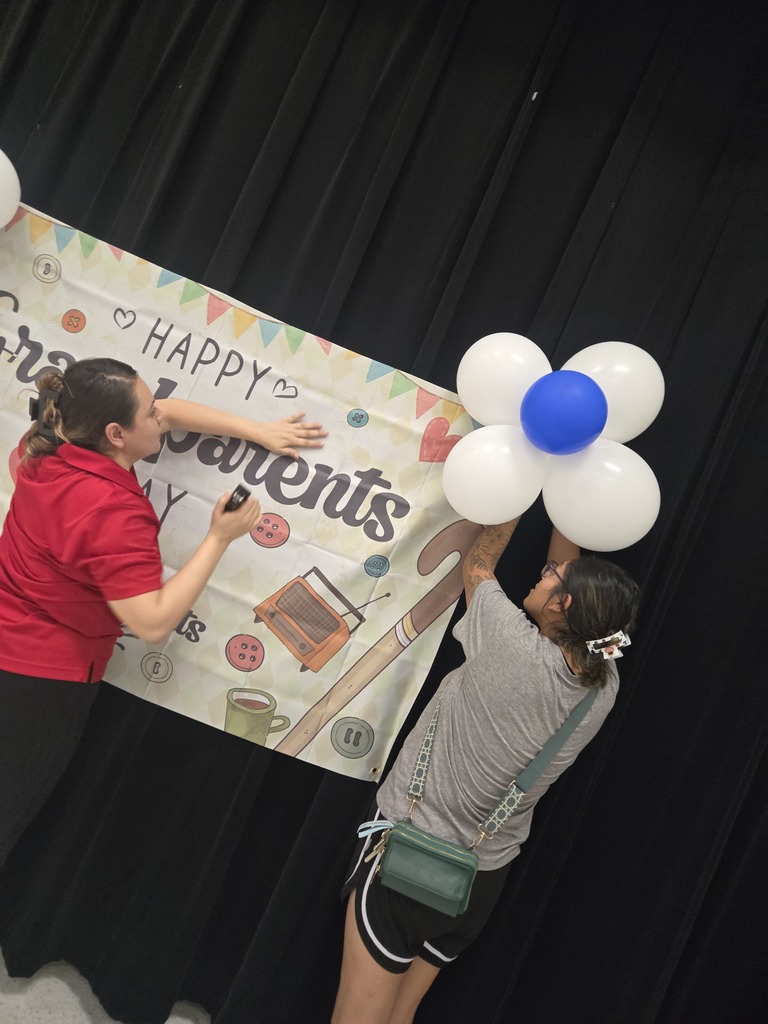 Volunteers help set up grandparents day banner and balloons