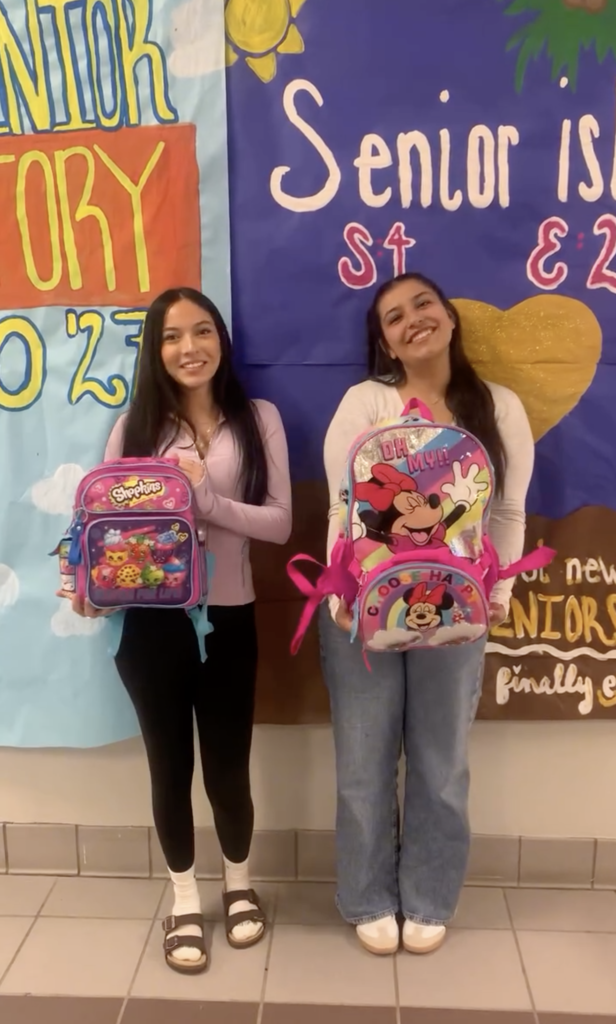 Two Chapin High School seniors hold children's backpacks and smiling for a photo