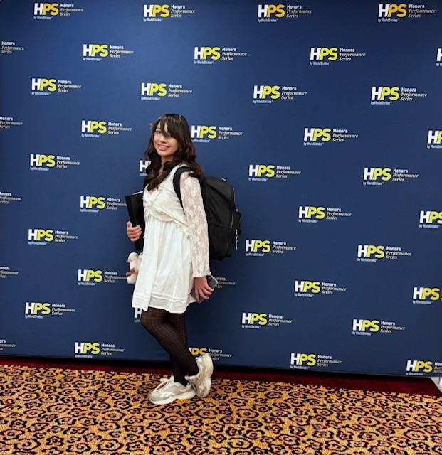 Vivian Lopez smiles with choir book in front of poster