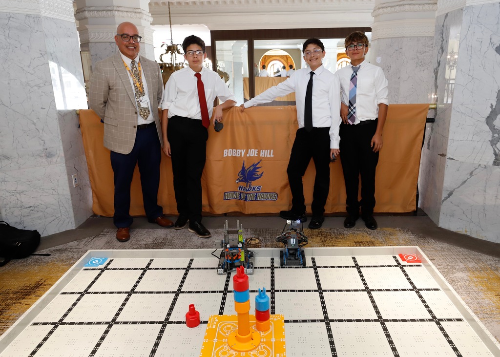 Bobby Joe Hill PK-8 robotics team smiles for a photo in front of their robotics display