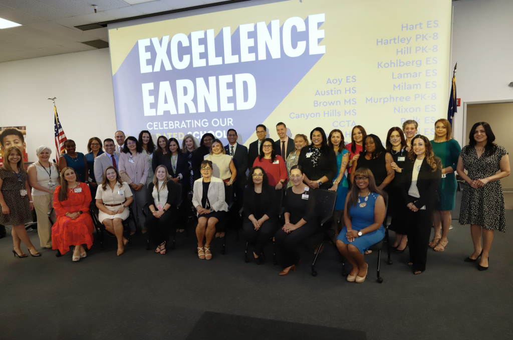 B rated campus principals take a group photo in front of screen that says Excellence Earned