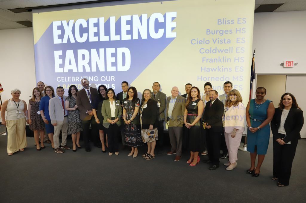 A rated campus principals take group photo in front of screen that says Excellence Earned