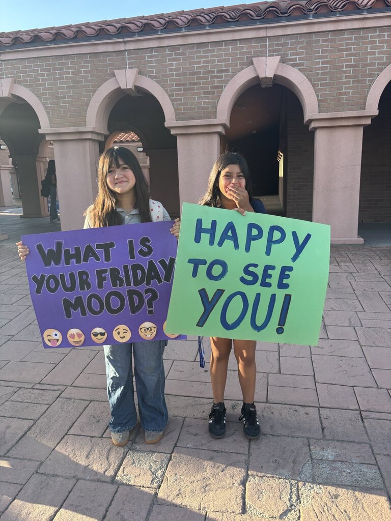 Guillen Middle School students holding up signs that say What is your Friday mood? Happy to see you!