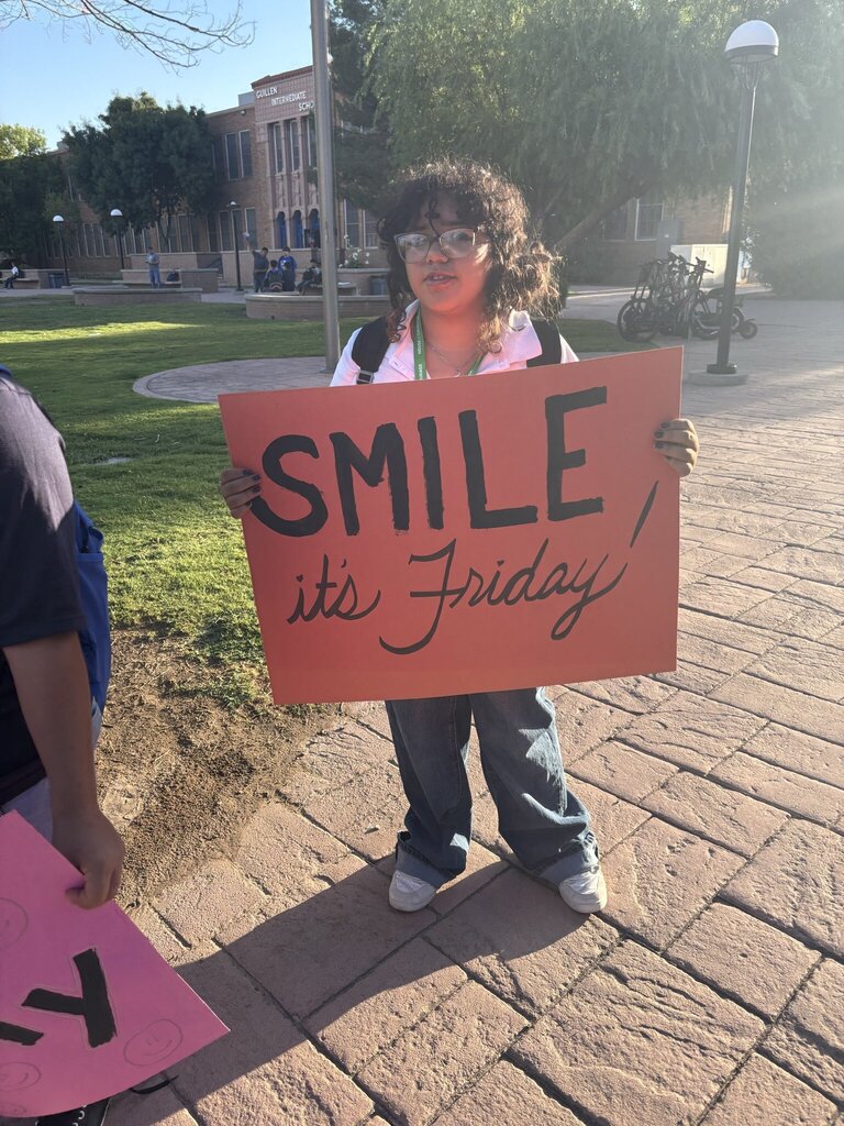 Guillen Middle School student holding up sign that says smile its Friday!
