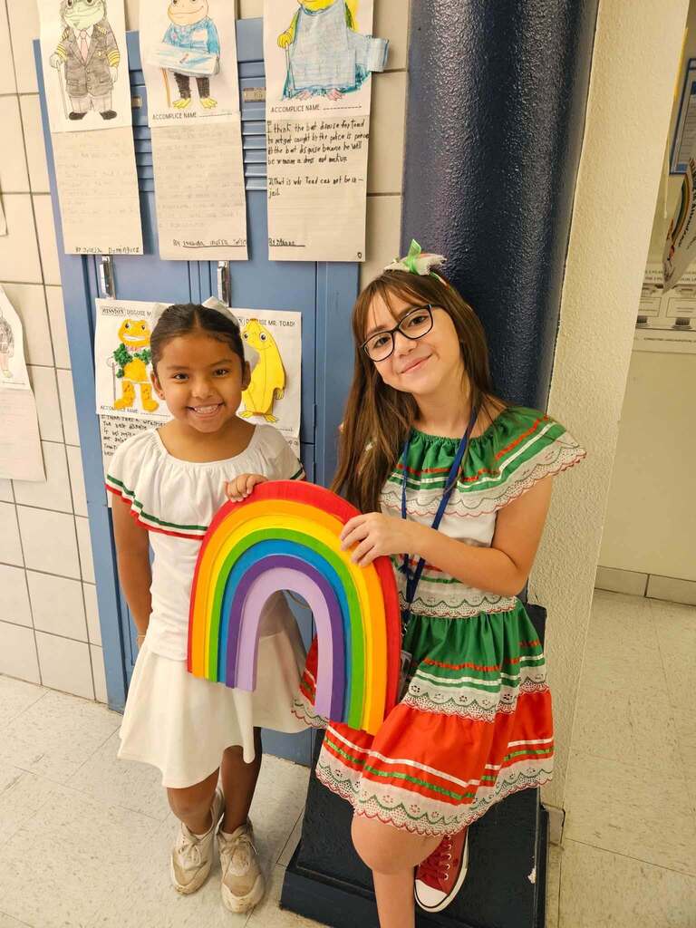 Whitaker Elementary School students take a photo dress in Mexican Independence Day attire while holding a rainbow (mascot)