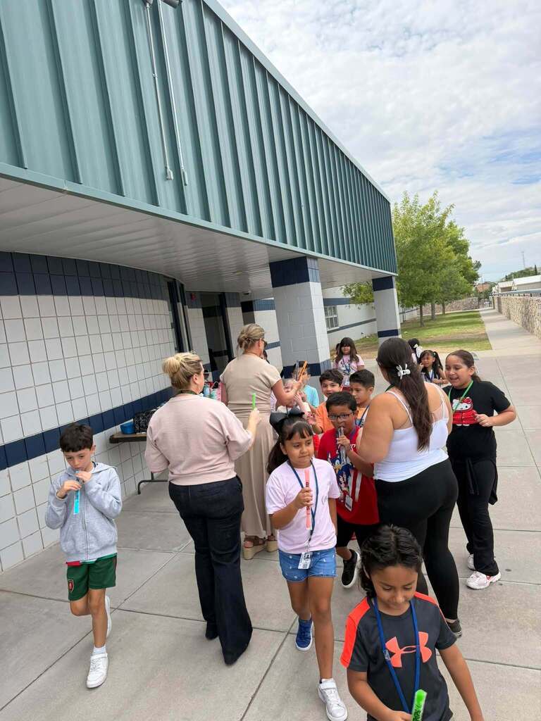 Staff members pass out ice pops to Kohlberg Elementary School students for Random Attendance Day