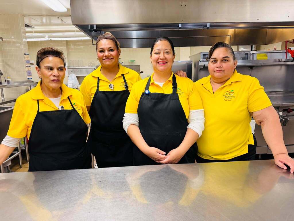 Cafeteria staff smile for a photo dressed in gold for Childhood Cancer Awareness Month