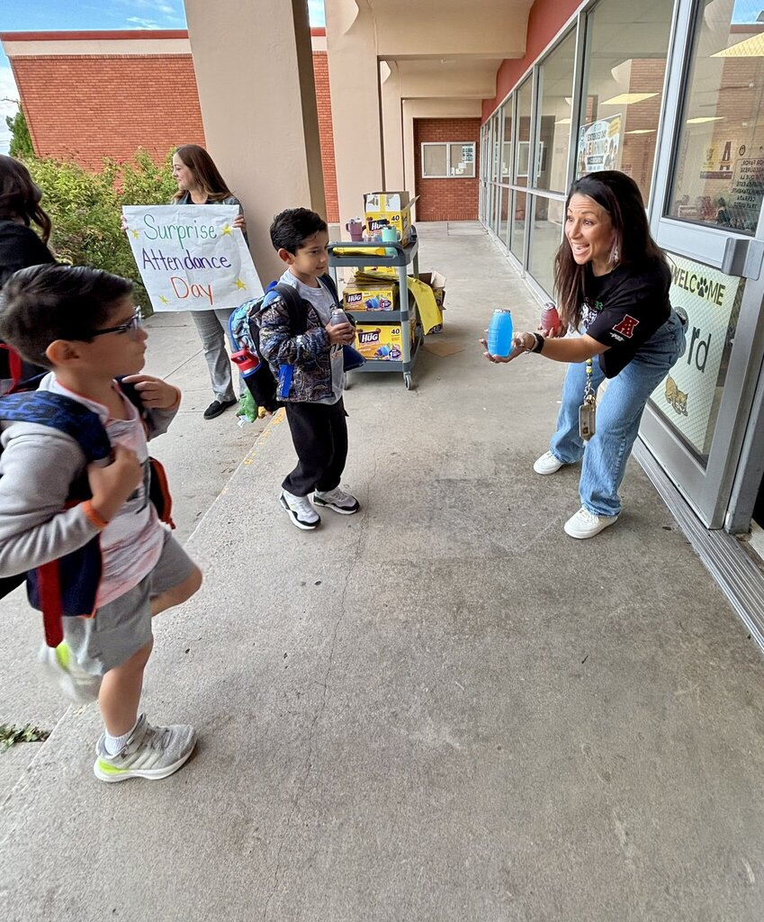 Cielo Vista Elementary School staff member hands juice boxes to students entering school