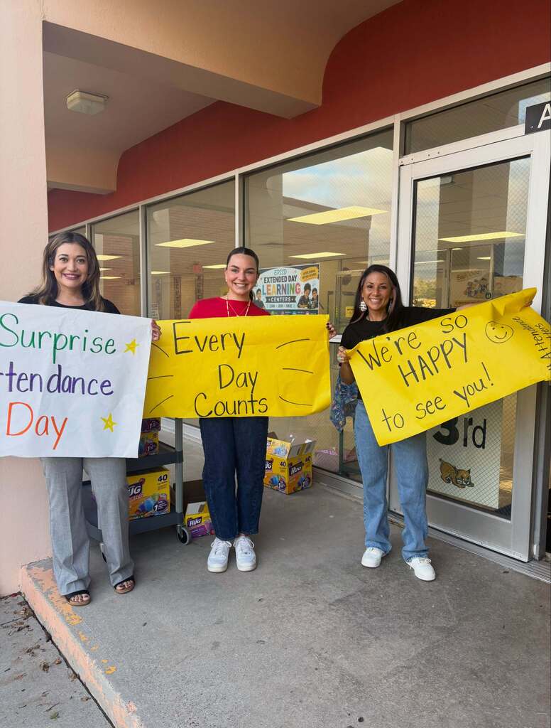 Cielo Vista Elementary School staff welcomes students into school with signs that say "Surprise Attendance Day" "Every day counts" and We're so HAPPY to see you!"