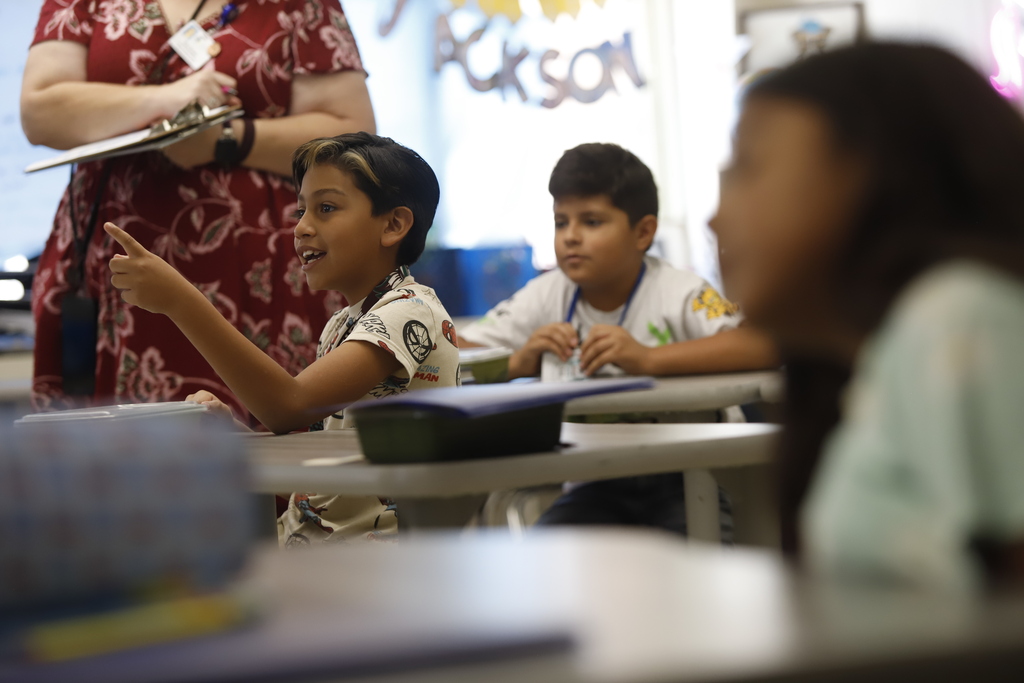Student pointing at screen smiling during class
