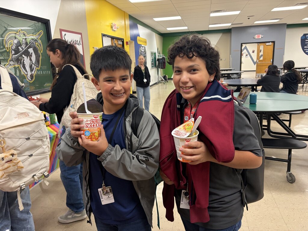 Two students smile with their cup of noodles