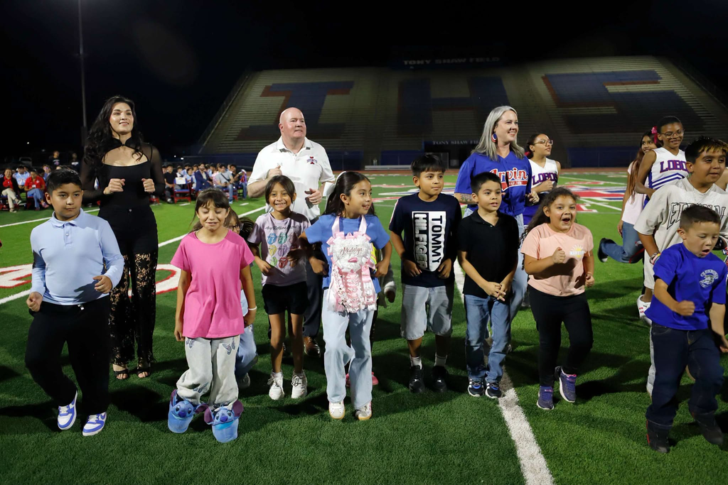 Stephanie Han jumps in the air alongside young students during the Irvin High School Homecoming parade
