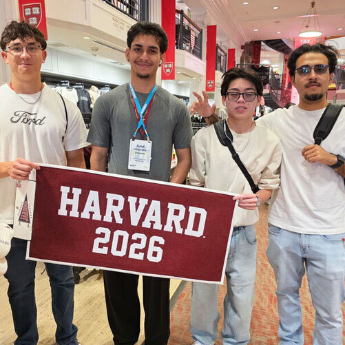 students hold up a sign that reads Harvard 2026