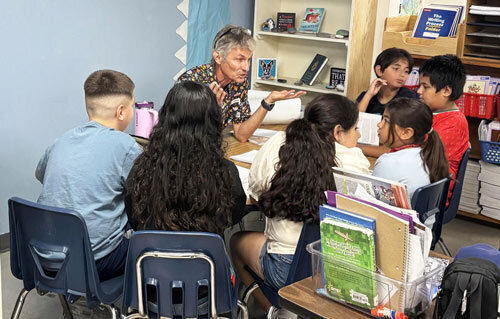 an image of a teacher sitting with students