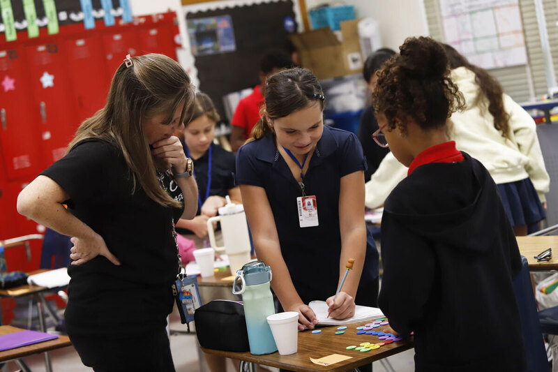 Students work next to their teacher