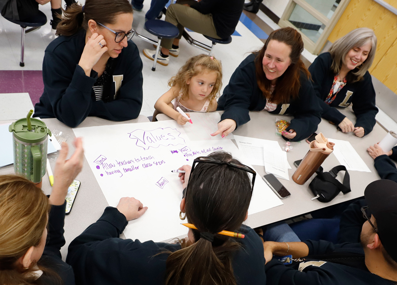 People stand around a table at a community meeting