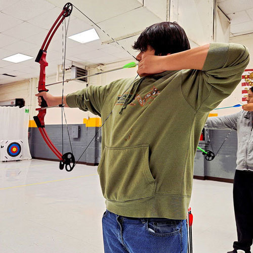 A student holds a bow and arrow