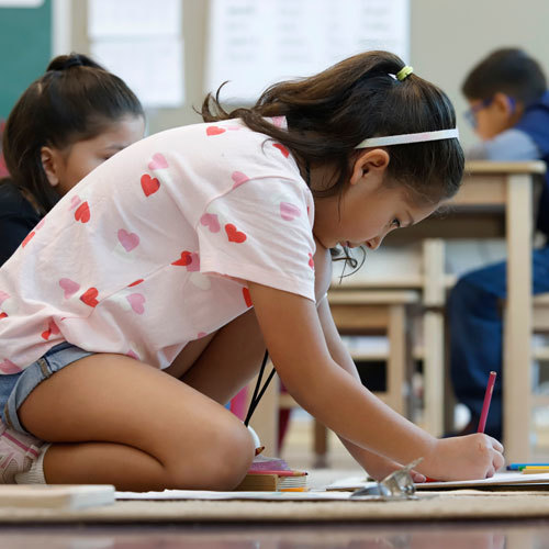 A student on the floor works on an assignment