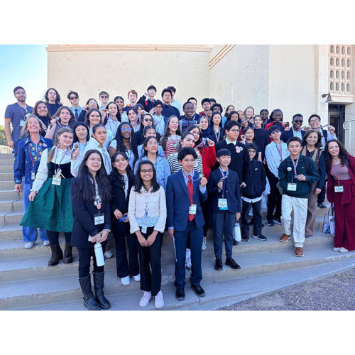 Several students stand on the steps of a venue