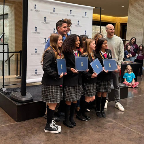 A group of students stand with awards