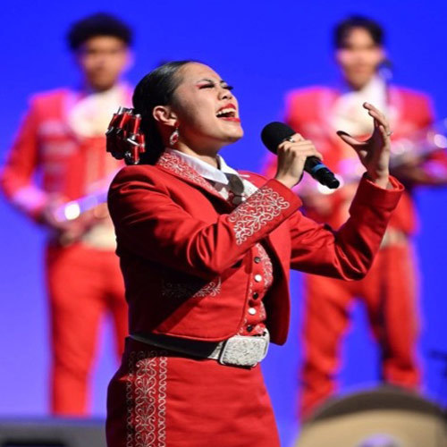 A mariachi singer sings into a mic