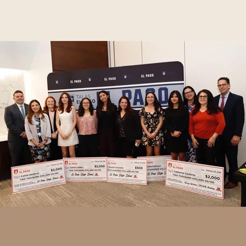 Various scholars post for a photo in front of large checks