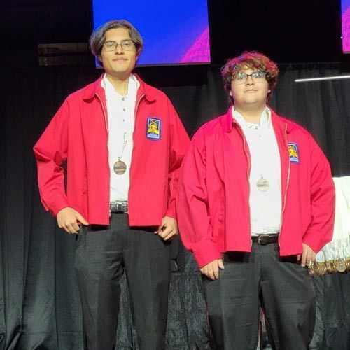 two students stand on stage