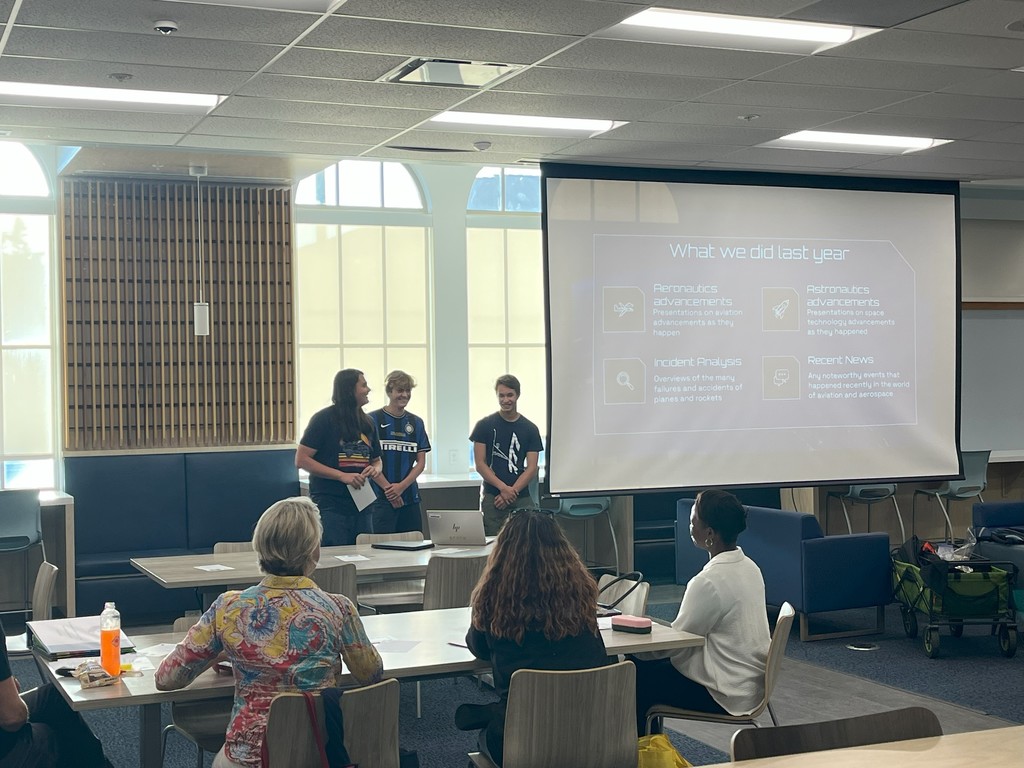 Students giving presentation with slideshow in front of audience.