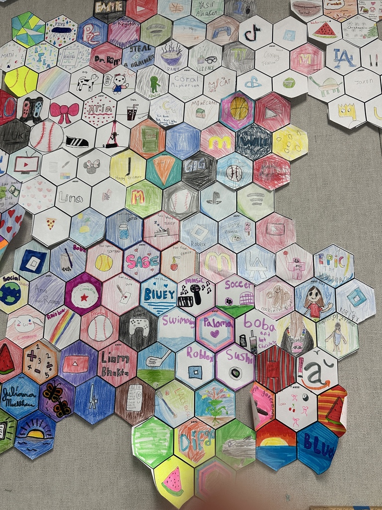 A large bulletin board covered with colorful hexagon-shaped drawings created by students.
