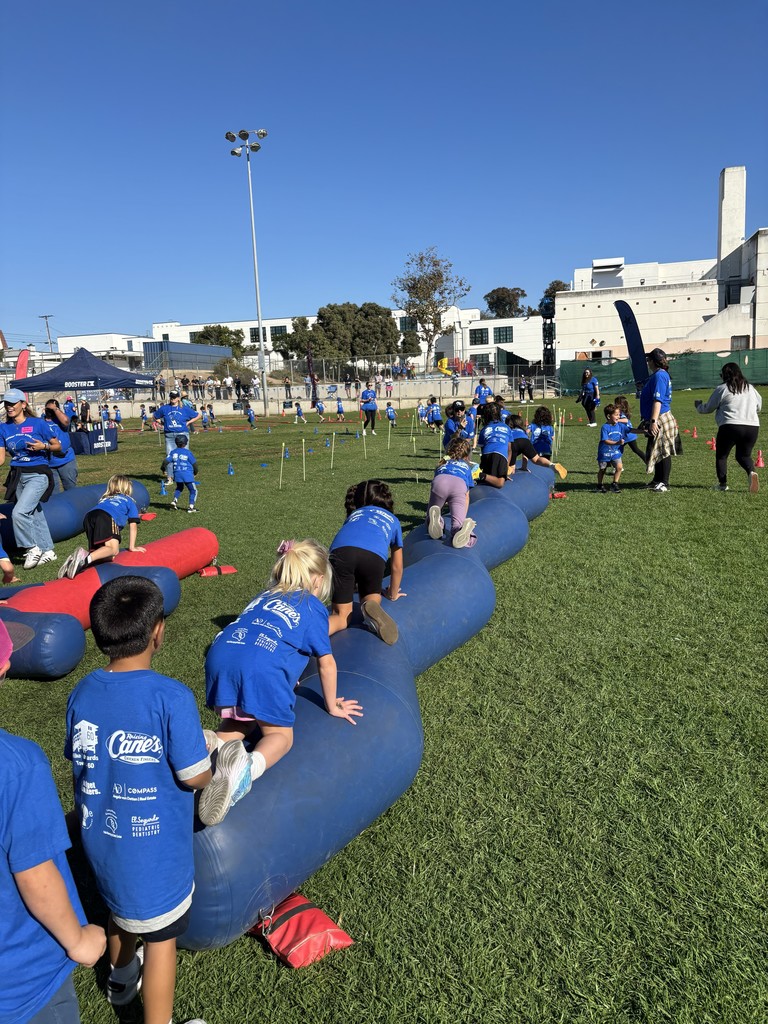 Children climb over a long inflatable obstacle on a field