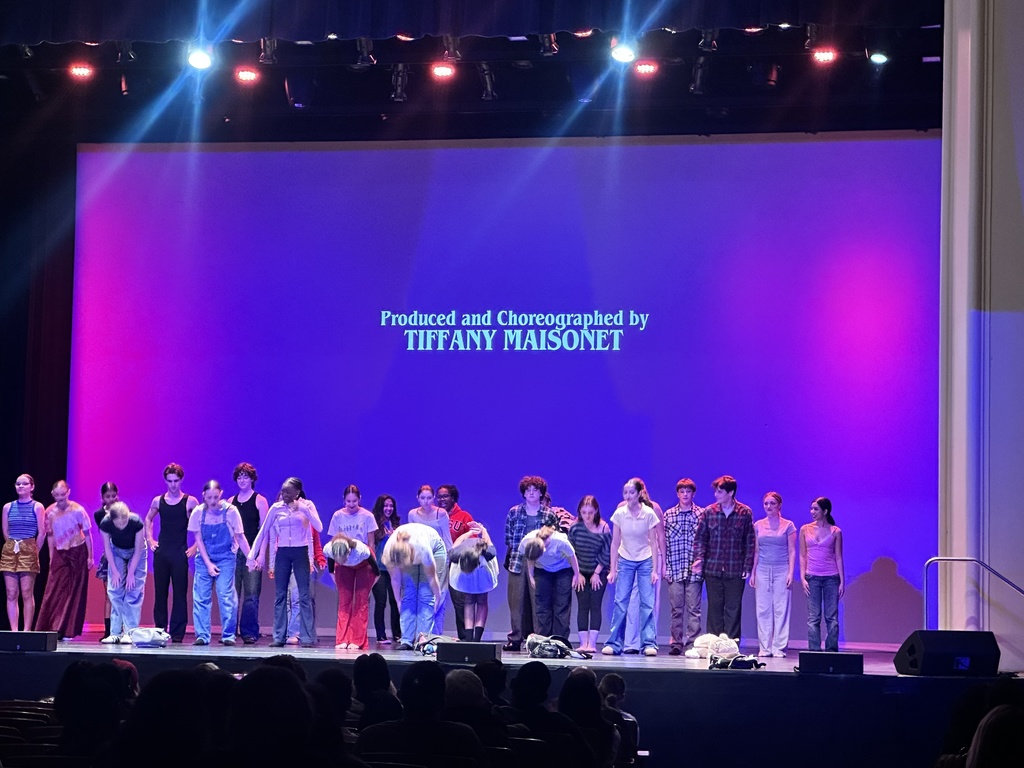 A large cast of performers takes a bow on stage during curtain call